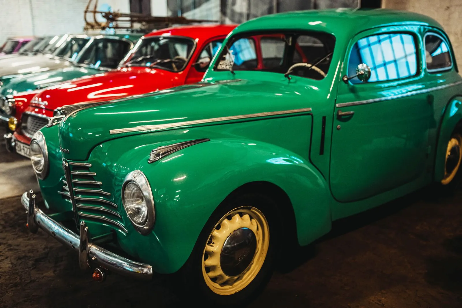 Mécanicien en bleu inspectant un moteur de voiture ancienne dans un atelier propre et lumineux